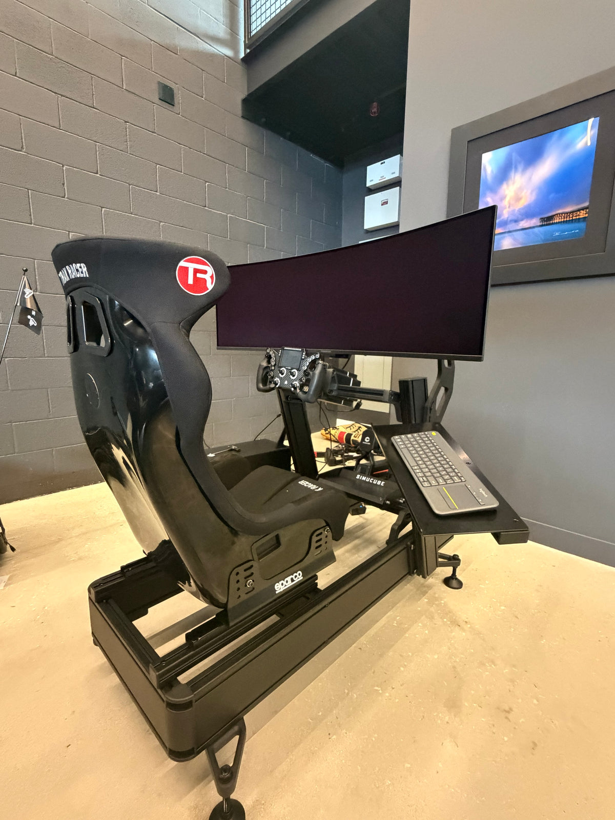 Completed sim racing build with a Simucube direct drive wheelbase, formula wheel, curved ultrawide screen and a keyboard tray on the side rail
